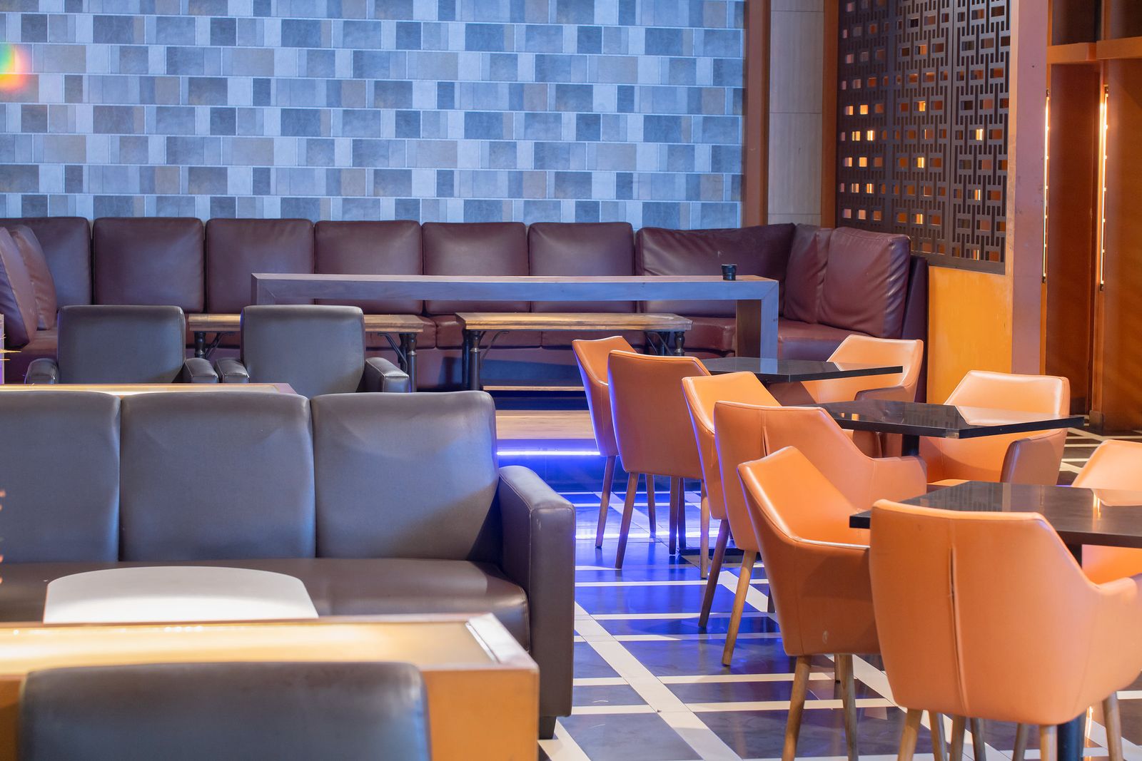 Sofa kulit dan lampu dinding hangat di area lounge